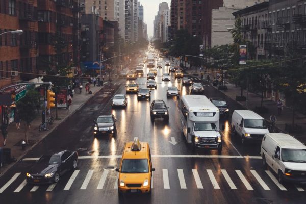 A bustling city street filled with cars, taxis, and buses navigating through the urban landscape.