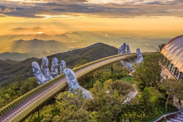 A stunning view of the Golden Bridge in Da Nang, Vietnam, featuring its iconic hands supporting the walkway against a blue sky.