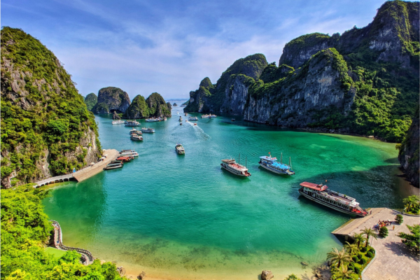 Boats anchored in calm waters beside a rugged rocky shoreline, showcasing a serene coastal landscape.