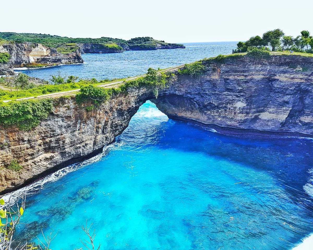 A serene view of the blue lagoon in Bali, showcasing vibrant turquoise waters surrounded by lush greenery.