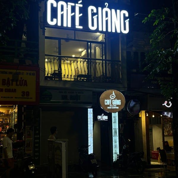 Night view of Café Giảng's neon-lit sign above the entrance.