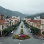 Approach to Da Lat City Center, French colonial architecture mixed with modern buildings, flower gardens, cool highland weather, clean streets, soft foggy atmosphere, scenic urban mountain city